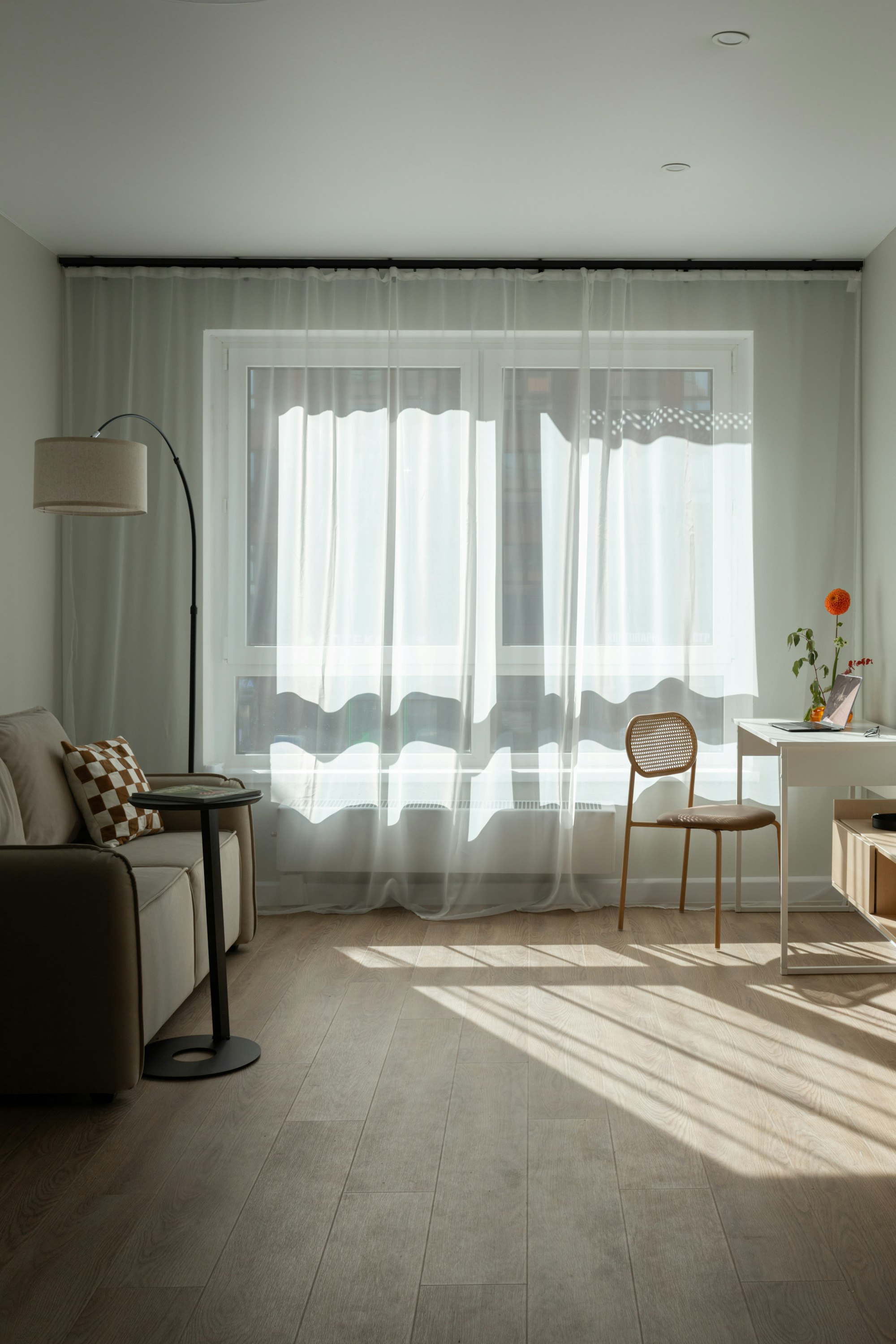 Sheer shades diffusing soft daylight across a calm, neutral living room